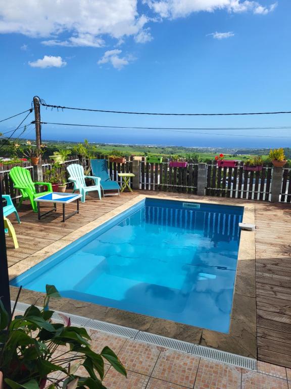 una piscina en una terraza con sillas y mesa en Villa letchi, en Entre-Deux