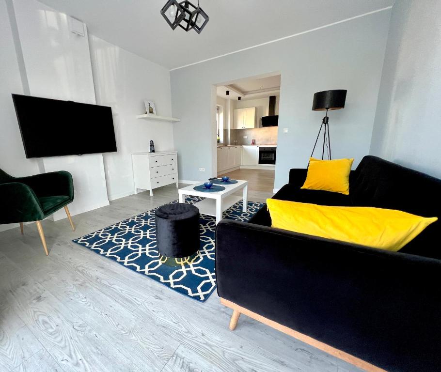 sala de estar con sofá negro y almohadas amarillas en Willa Apart, en Władysławowo
