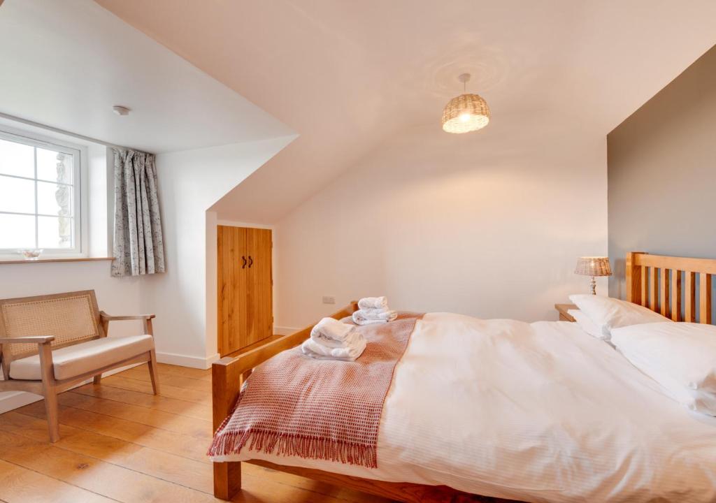 a bedroom with a bed and a chair and a window at Llys Bach in Llanarmon