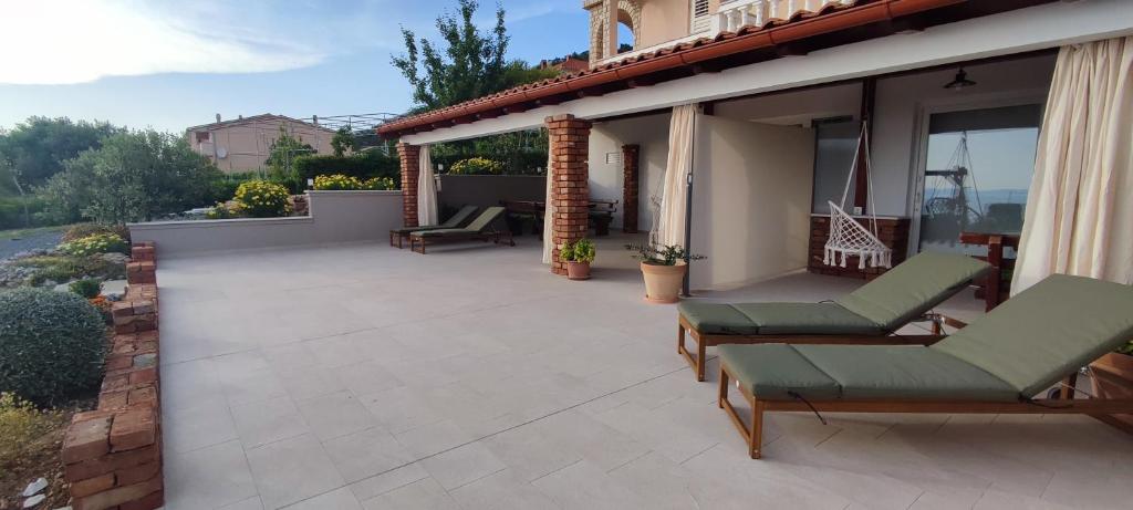 a patio with chairs and a house at Apartments Tinjarosa in Mundanije