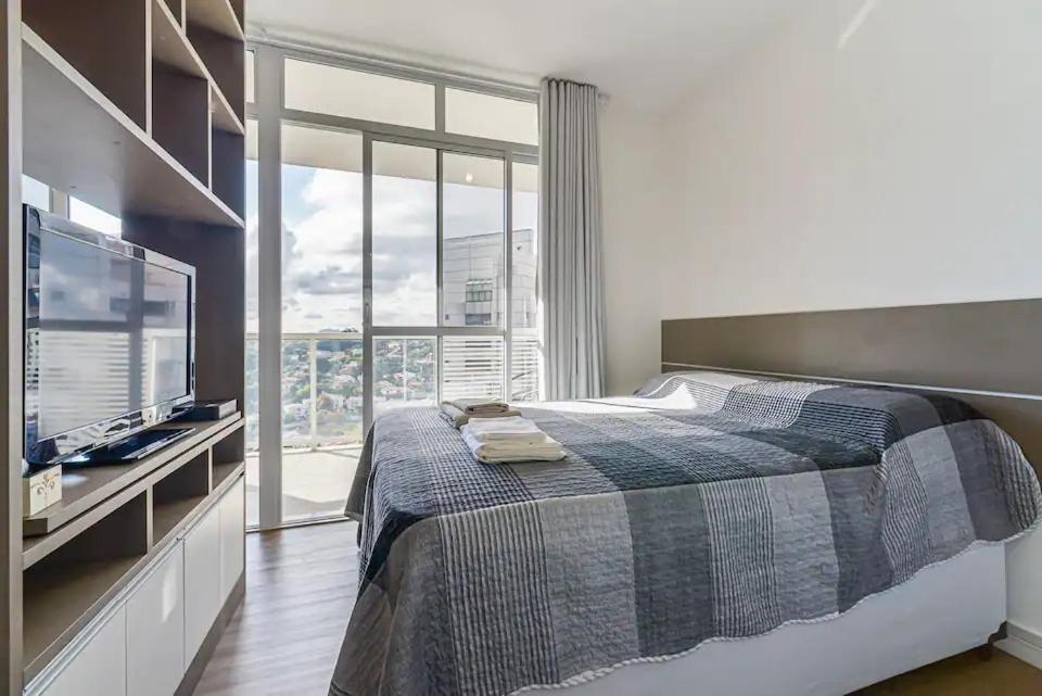 a bedroom with a bed and a large window at Flat Completo na Ponte Estaiada SP in Sao Paulo