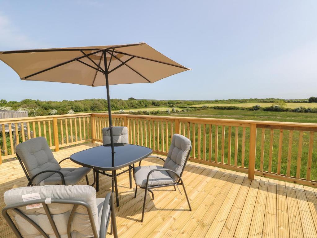 a patio table with chairs and an umbrella on a deck at Mountain View Lodge 2 in Holyhead