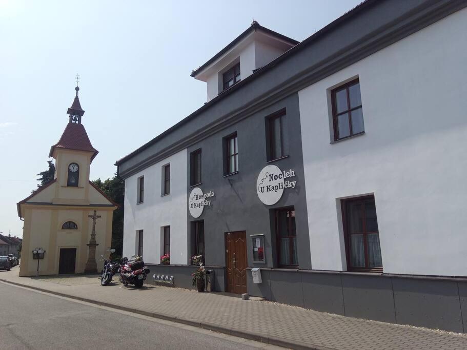 ein weißes Gebäude mit einem Uhrturm neben einer Straße in der Unterkunft Nocleh U Kapličky 
