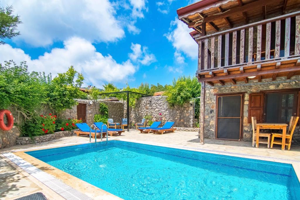 a house with a swimming pool and a patio with blue chairs at Havuzu korunaklı 2+1 taş villa in Kınalı