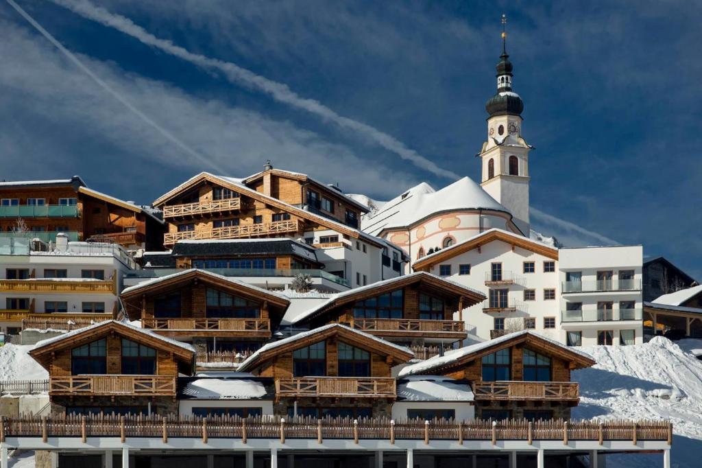 un grupo de edificios con una torre de reloj en una montaña en PUR Suites & Chalets en Lermoos