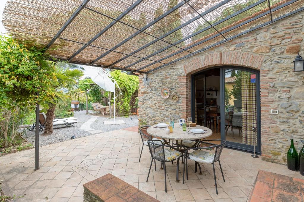 a patio with a table and chairs under a pergola at Casale Rosmarino in Suvereto