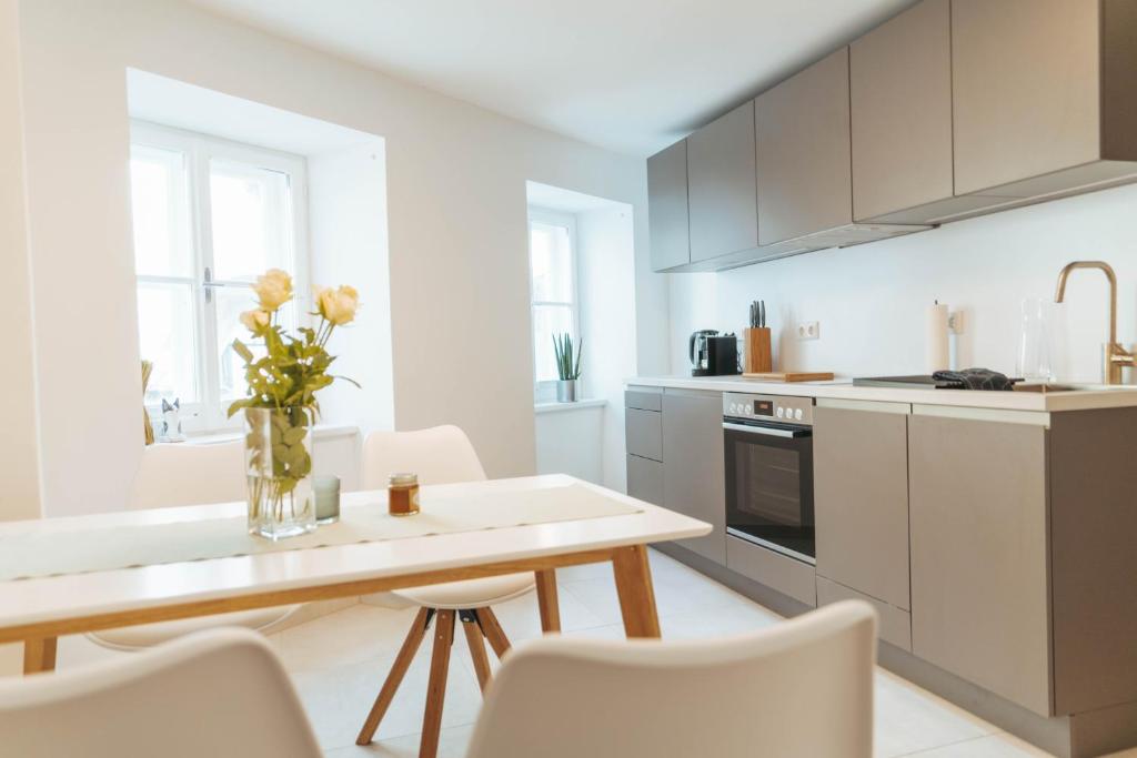 a white kitchen with a table and a vase of flowers at Apartment an der Rugenstiege in Steiner Altstadt in Krems an der Donau