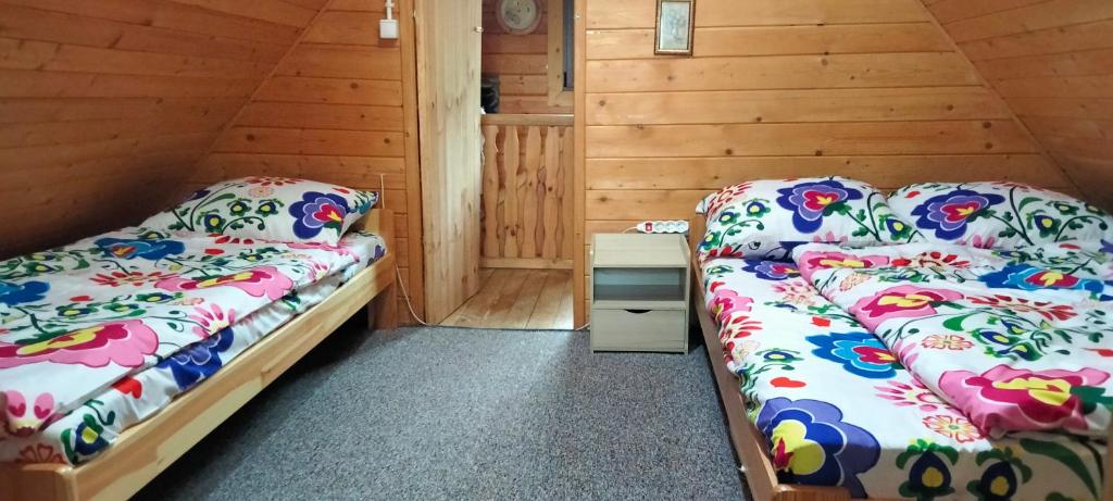 2 łóżka w pokoju z drewnianymi ścianami w obiekcie Domek Dzięciołek w mieście Życiny