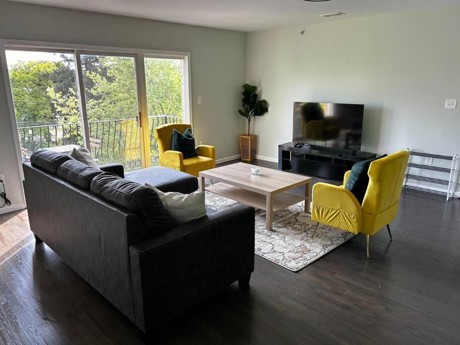 a living room with a couch and a table and yellow chairs at Spacious Master Bedroom in Newark