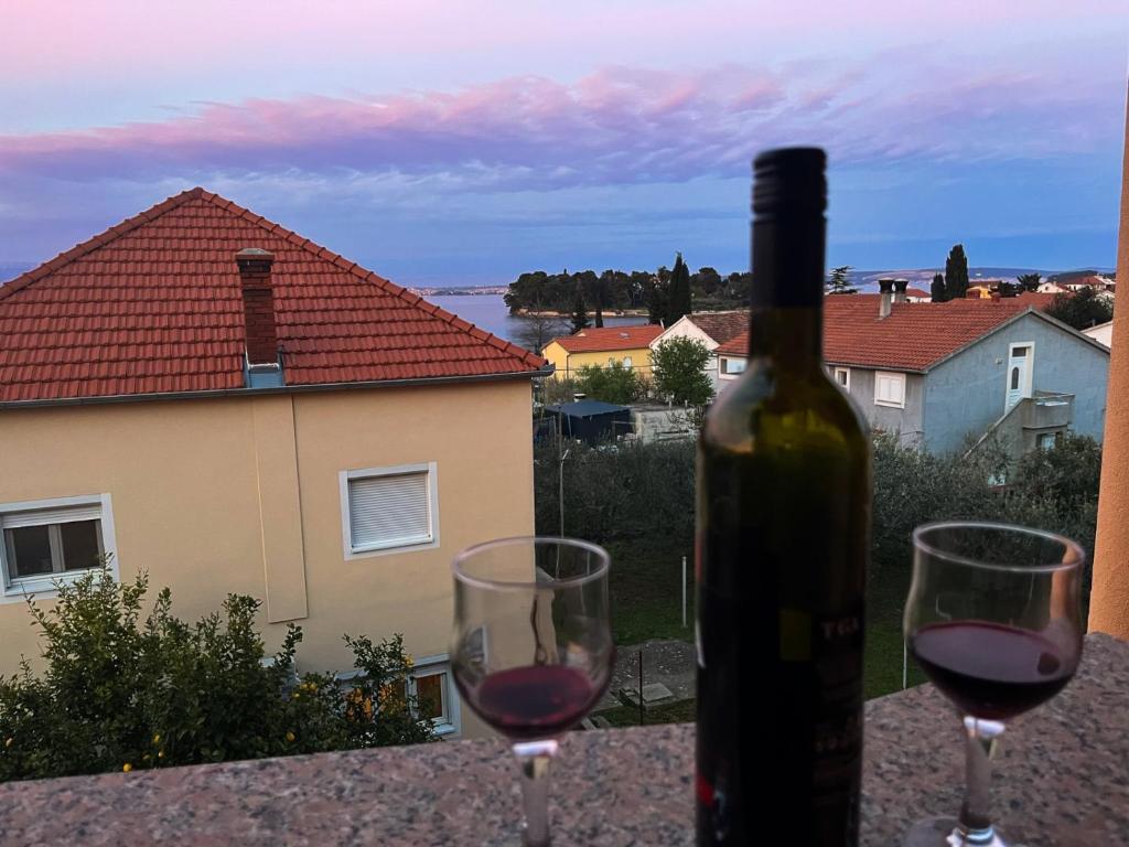 Una botella de vino y dos copas en una mesa. en Adriatic Oasis Apartments en Preko