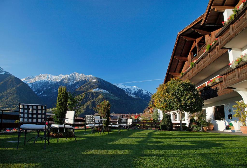 een gazon met stoelen en bergen op de achtergrond bij Hotel Walder in Schenna