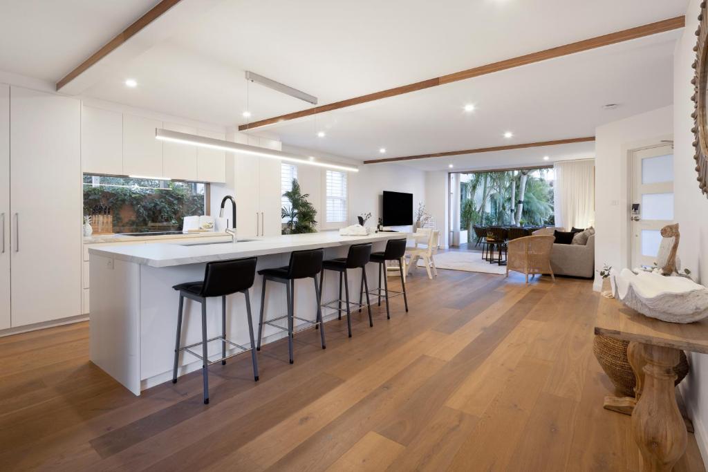 a kitchen and living room with a bar with stools at Beach Retreat in Sydney