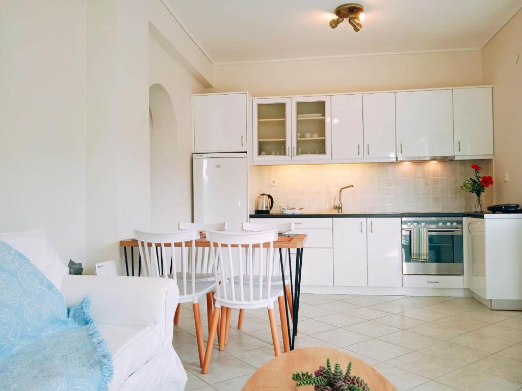 a kitchen with white cabinets and a table and chairs at Mochlos Essence Apartments in Mochlos