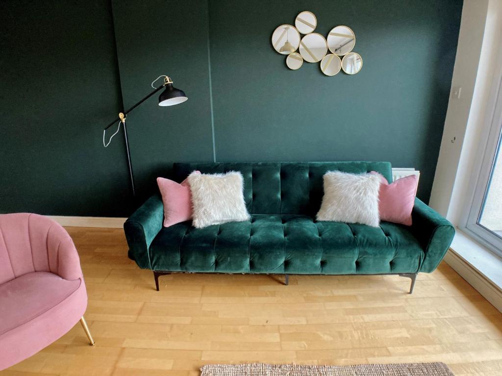 uma sala de estar com um sofá verde com almofadas cor-de-rosa em Little Victoria Apartments em Belfast