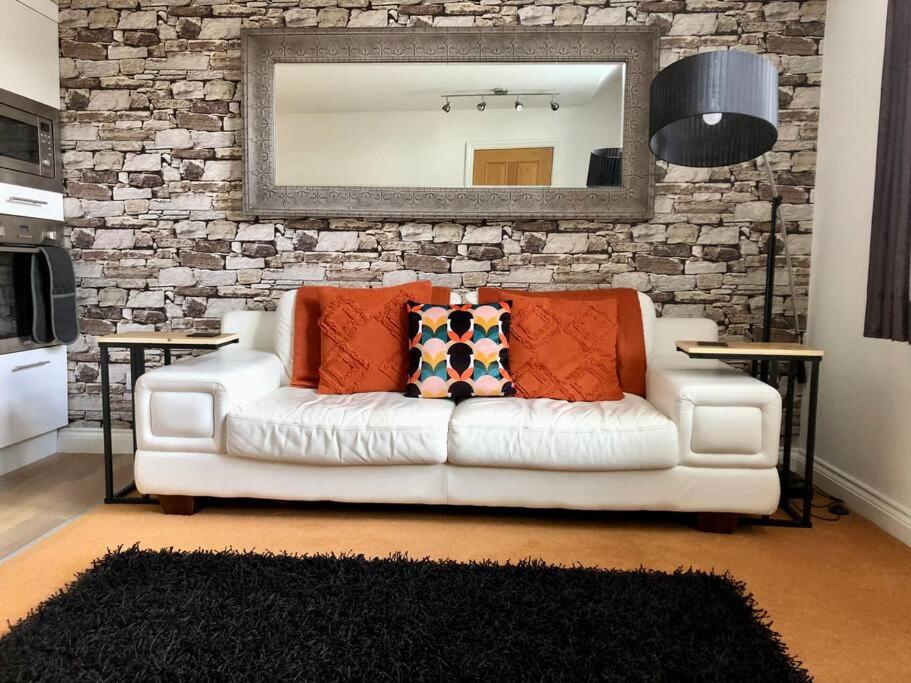 a living room with a white couch and a mirror at Bank Building Apartments in Barnoldswick