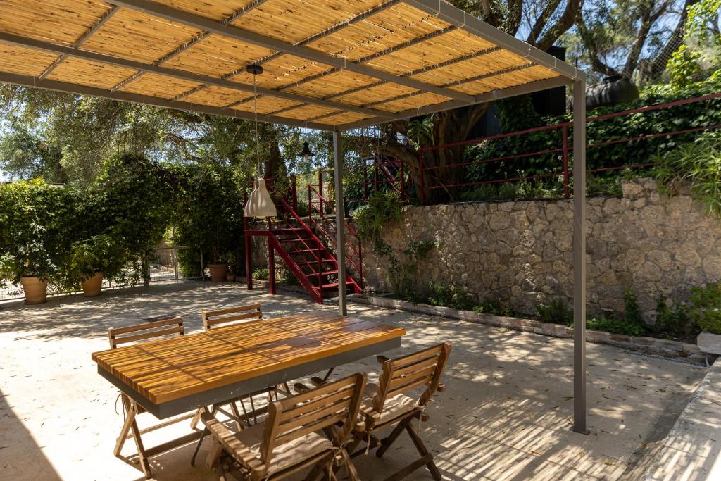 a wooden table and chairs under a wooden pergola at Paleokastritsa Red Gate Flat in Paleokastritsa