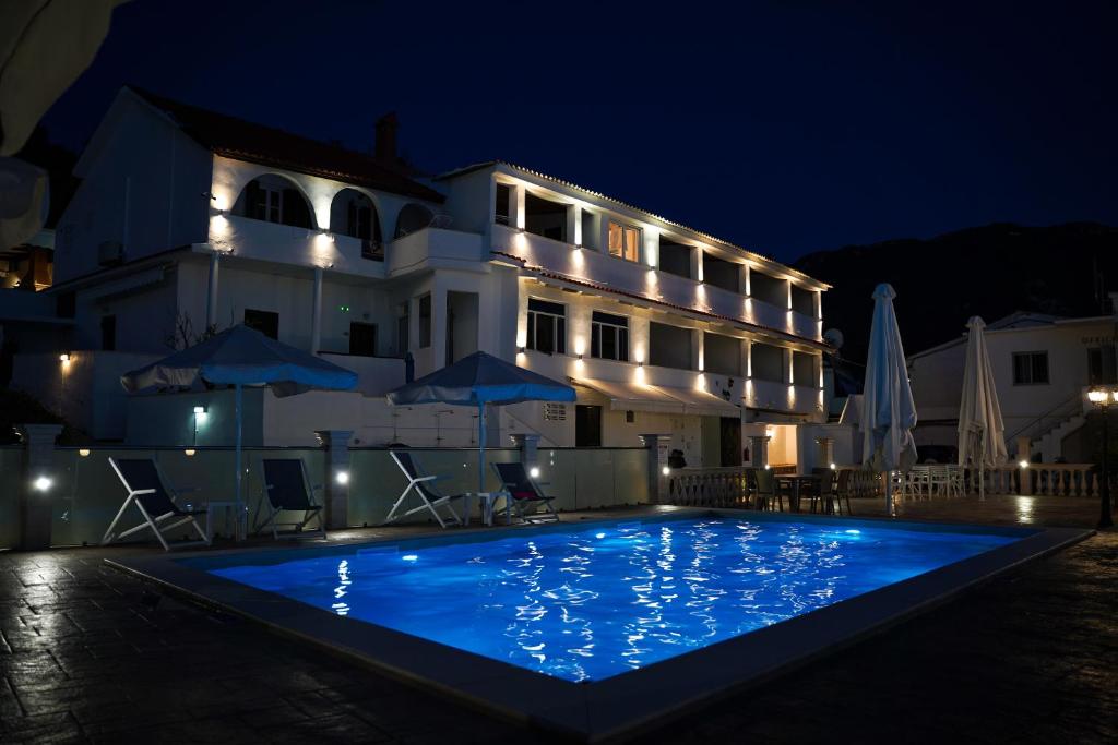 a hotel with a large swimming pool at night at Kostas Beach Apartments in Agios Gordios