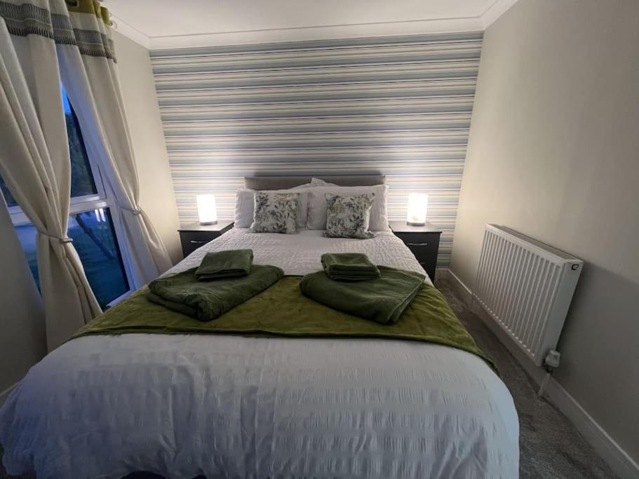 een slaapkamer met een groot bed met 2 groene kussens bij Elora's Dream in Wisbech