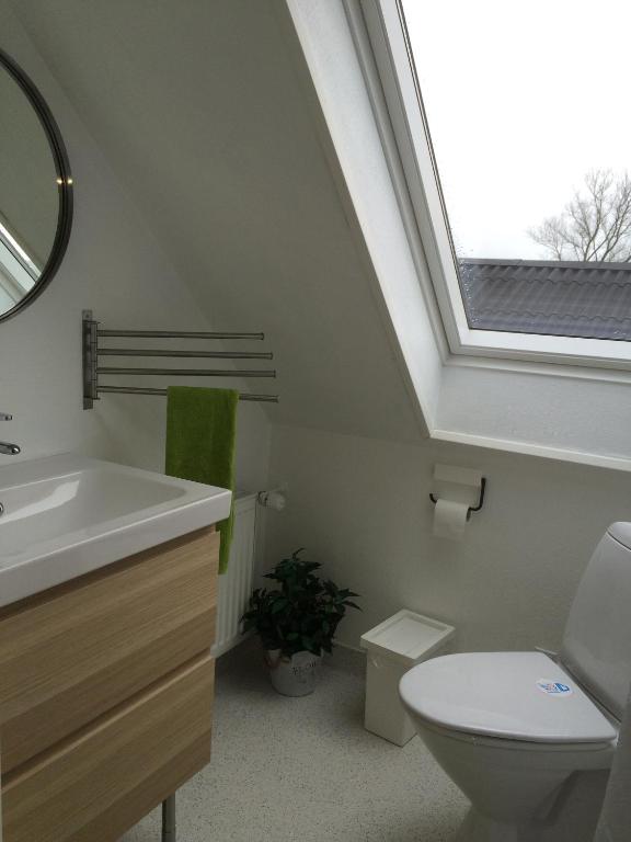 Un baño con lavabo, inodoro y ventana. en Svalegaarden Guesthouse, en Særslev