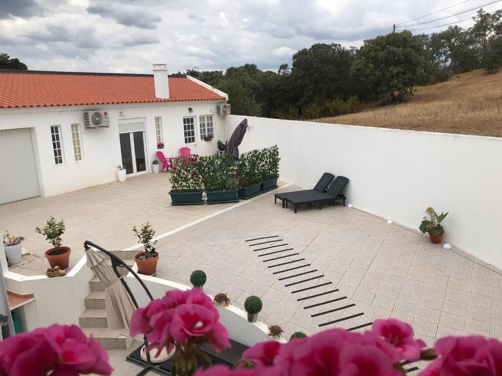 eine Terrasse mit rosa Blumen und einer weißen Wand in der Unterkunft Le Nid D’Abela in Abela