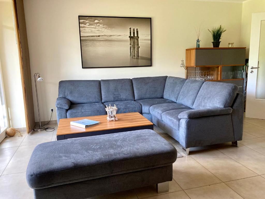 a living room with a blue couch and a table at Ferienhaus Grodenblick Strandflieder Whg. 2 in Wangerooge