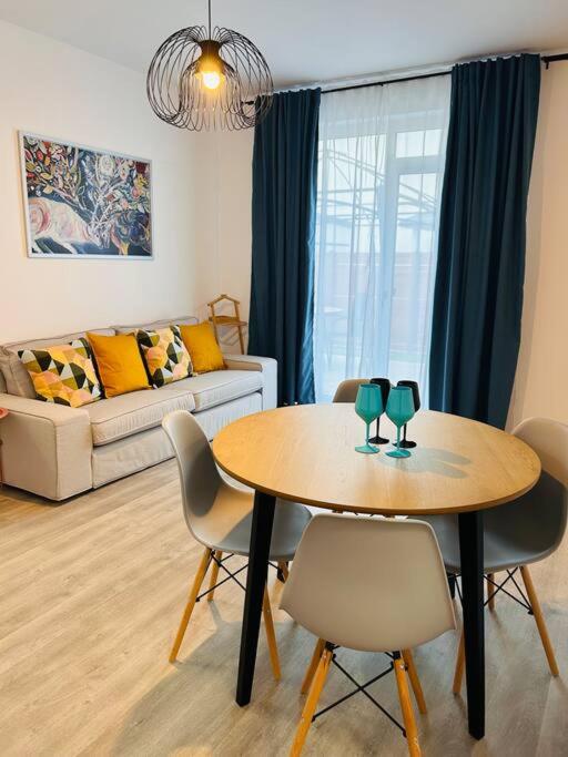 - un salon avec une table, des chaises et un canapé dans l'établissement Apartment #12lunipebega Timisoara, à Timişoara