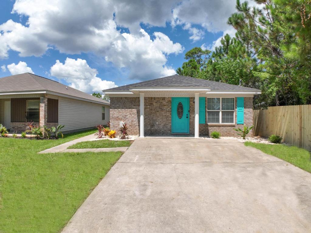a house with a blue door in a yard at Bungalow 1mile from Beach TVs Games Backyard in Navarre