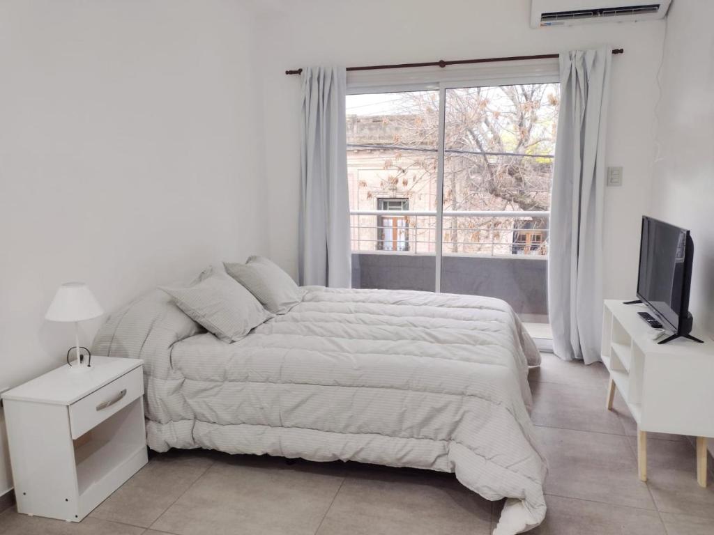 a white bedroom with a bed and a window at DTo CÉNTRICO LOBOS 1 B in Lobos