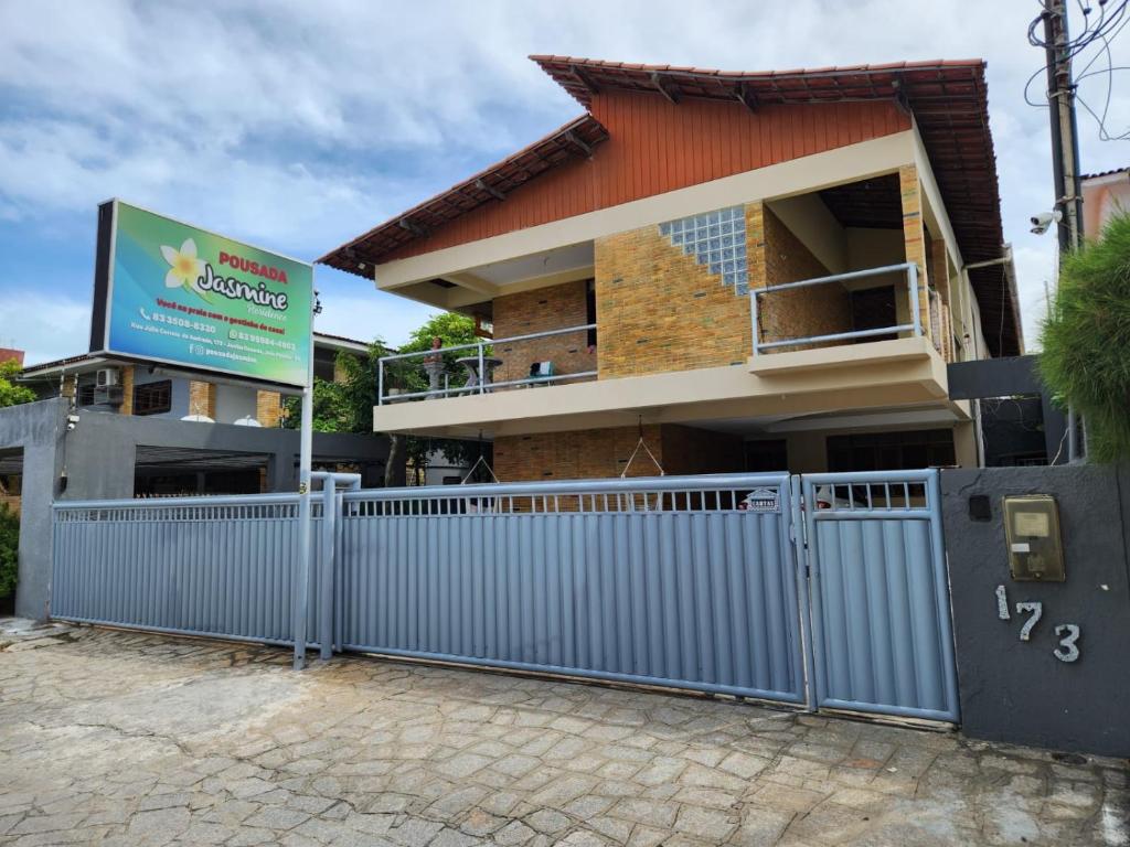 a house with a blue fence in front of it at Pousada Jasmine in João Pessoa