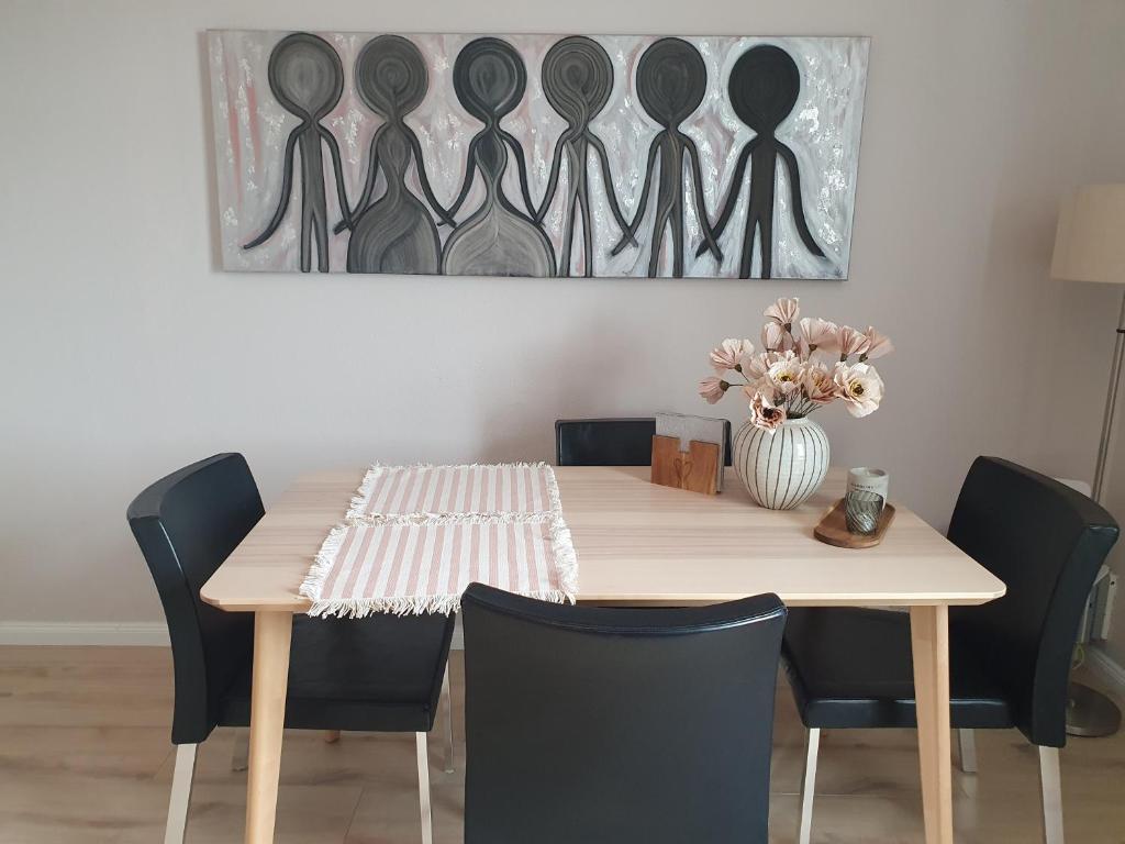 a dining room table with chairs and a vase of flowers at Cosy apartment in the old west Reykjavik center in Reykjavík