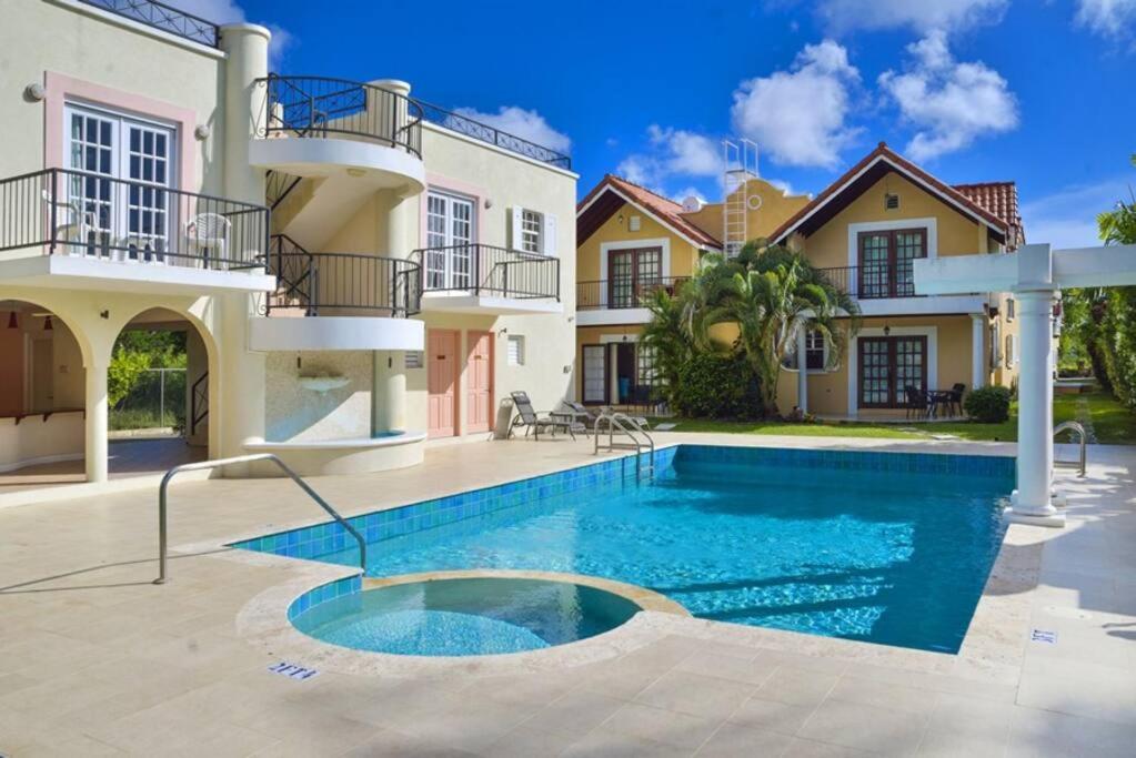 a villa with a swimming pool in front of a house at STUDIO Apt Bright comfy with pool on South Coast in Bridgetown