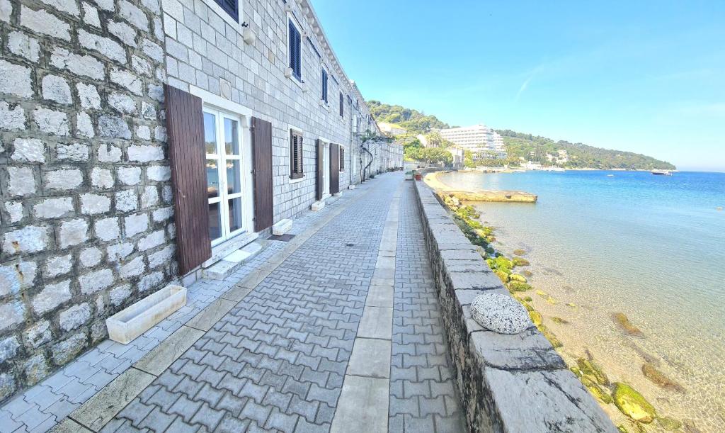 einen Backsteinsteig neben einem Gebäude neben dem Wasser in der Unterkunft Emerald Beloc House Lopud Island in Lopud Island