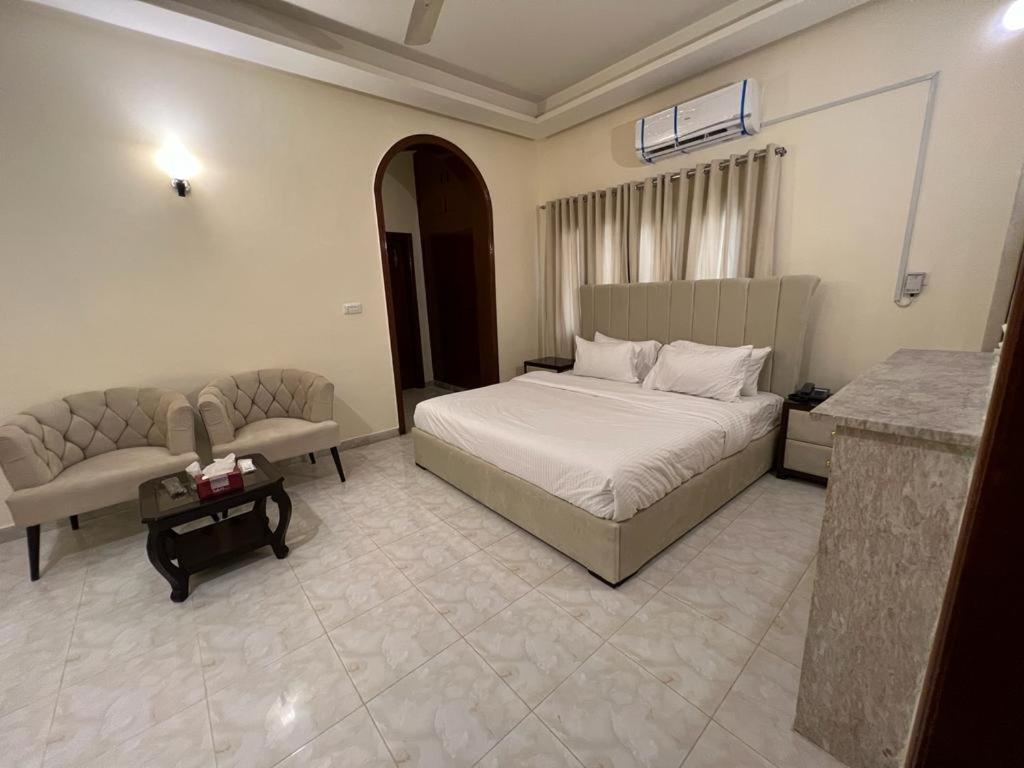 a bedroom with a bed and a couch and a table at Heritage Inn in Islamabad