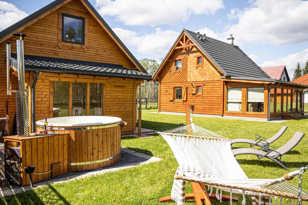 Cabaña de madera con bañera de hidromasaje y sillas en un patio en Uroczysko Lubajny, en Idzbark