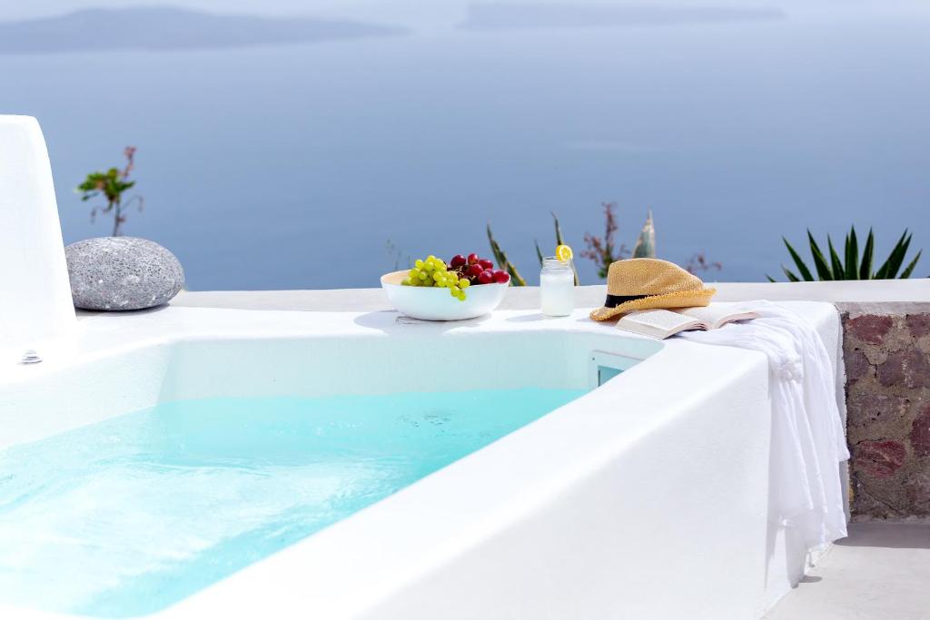 a swimming pool with a table and a bowl of fruit at Cleo's Dream Villa in Oia
