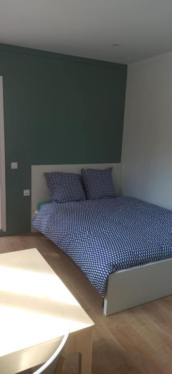 1 dormitorio con 1 cama con pared verde en studio tout équipé, en Saint-Étienne-de-Montluc