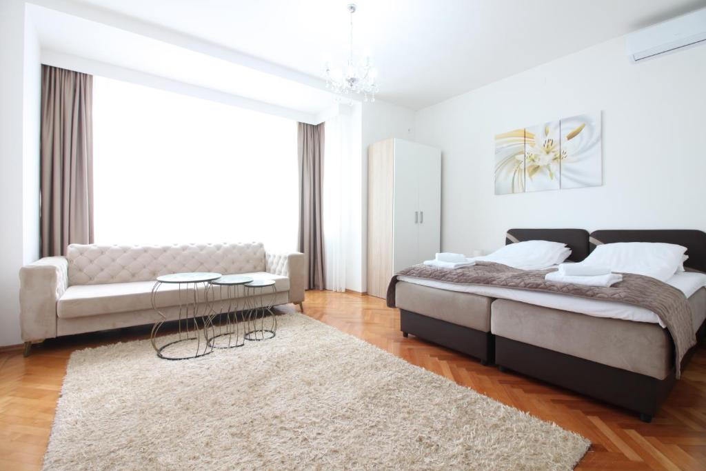 een slaapkamer met een bed, een bank en een tapijt bij Apartment Roma at Bascarsija in Sarajevo