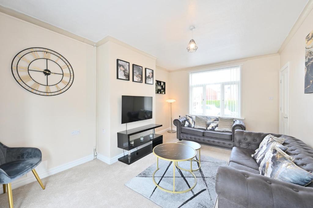 a living room with a couch and a clock on the wall at Sleek 3 Bed in Bolton- Sky channels & BT sports in Bolton