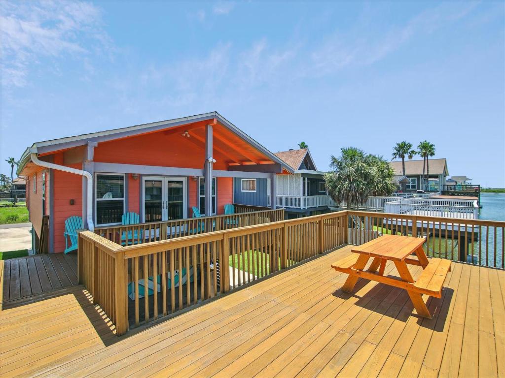 a wooden deck with a picnic table and a house at Amigo Bay in Galveston