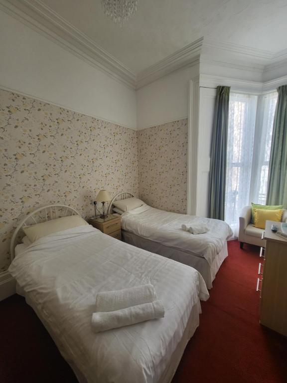 una habitación de hotel con 2 camas y una silla en Florence Guest House, en Weston-super-Mare