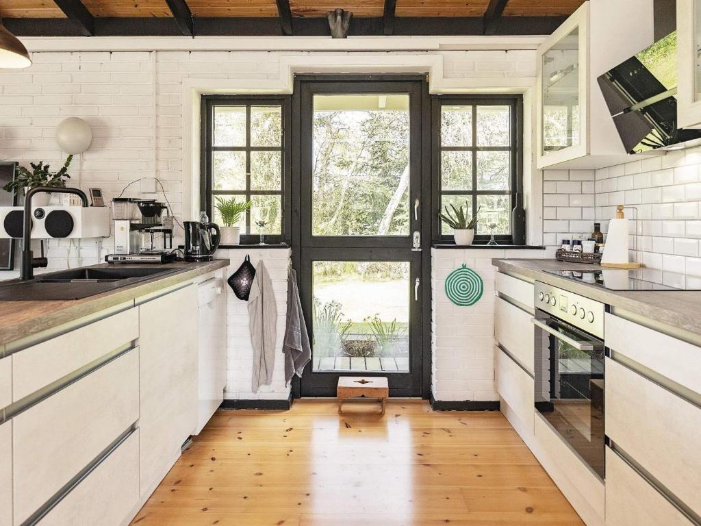 a kitchen with white cabinets and a large window at Holiday home Væggerløse VII in Marielyst