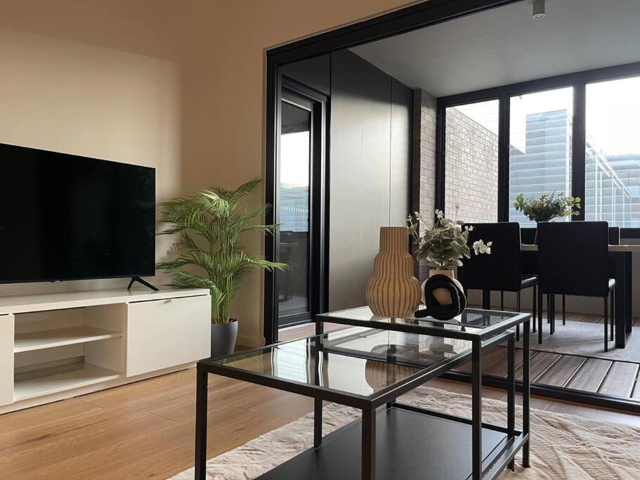 sala de estar con TV de pantalla plana y mesa en Modern luxurious unit in the heart of Dickson en Canberra
