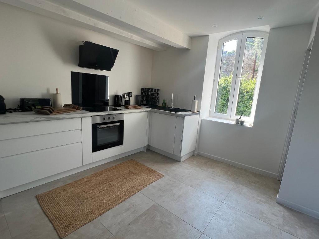 a kitchen with white cabinets and a window at Appartement spacieux et agréable in Callian