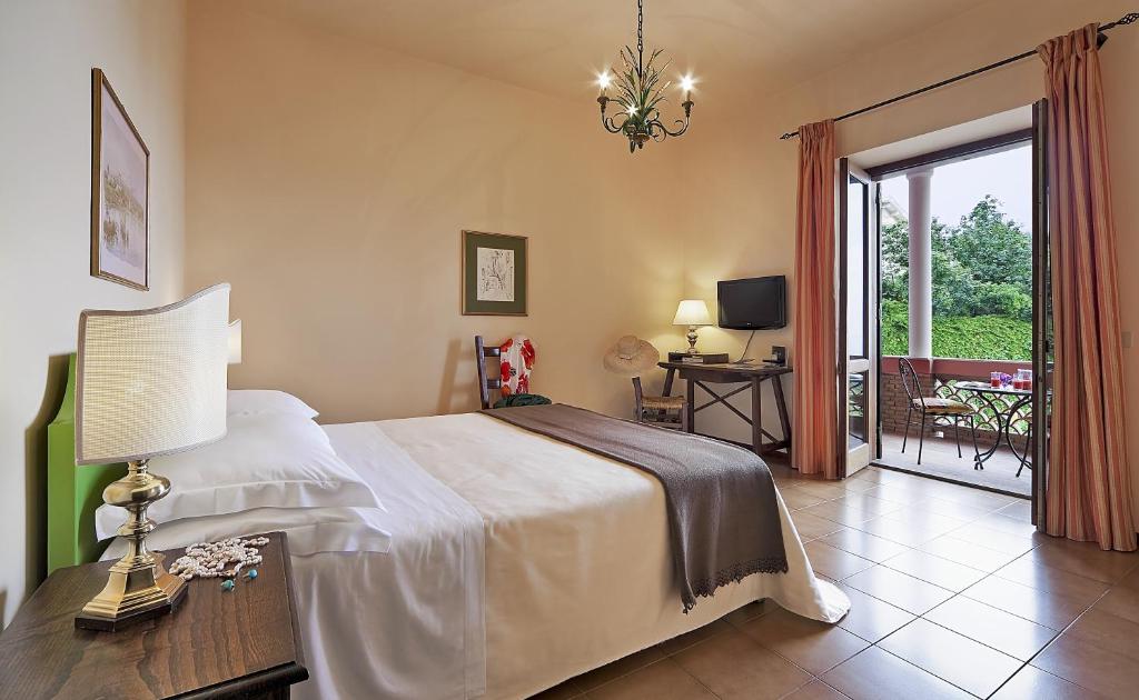 a bedroom with a bed and a table with a lamp at Hotel Villa Sirina in Taormina