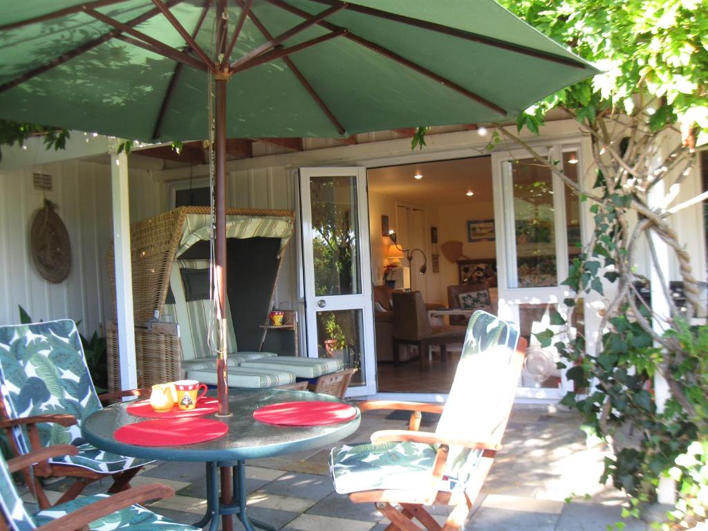 a table with a green umbrella on a patio at Aimeo Cottage in Russell