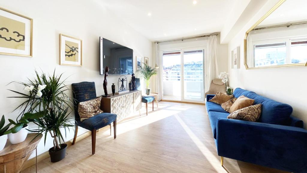 uma sala de estar com um sofá azul e uma televisão em Paradise Luxurious flat, free parking, 3 double rooms, terrace, jacuzzi, fully renovated em San Sebastián