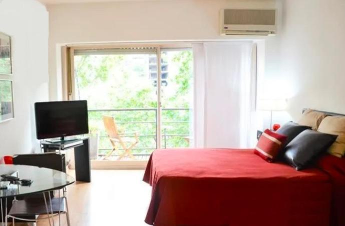 a bedroom with a red bed and a table and a window at Corrientes y Riobamba in Buenos Aires