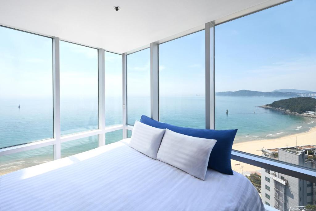 een slaapkamer met een bed en uitzicht op de oceaan bij Kolon Seacloud Hotel in Busan