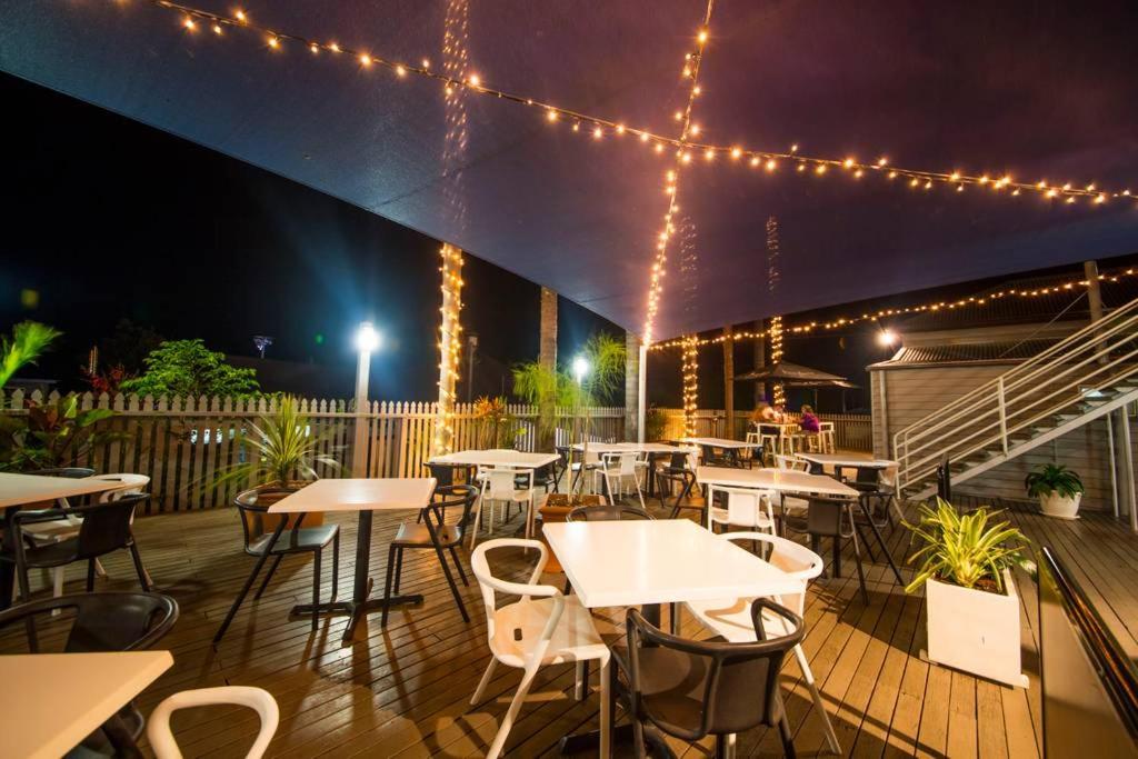 un restaurante con mesas y sillas en una terraza por la noche en The Australian Hotel, en Gympie