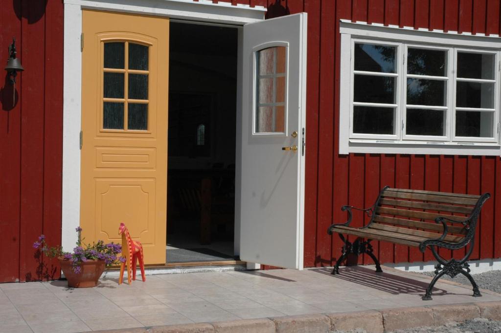 un banc à côté d'un bâtiment rouge avec une porte jaune dans l'établissement Sundsmåla Landsbygdshotell, à Brokind